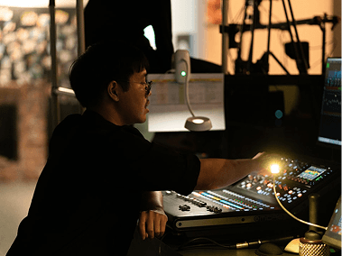 Person adjusting controls on sound mixing board